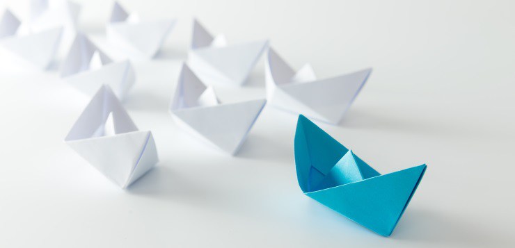 Leadership concept using blue paper ship among white